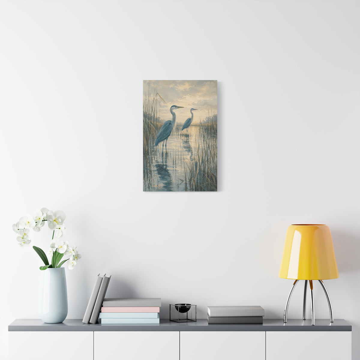 Two in the Reeds canvas print — Two herons stand among reeds and still water, one slightly forward and one farther back.